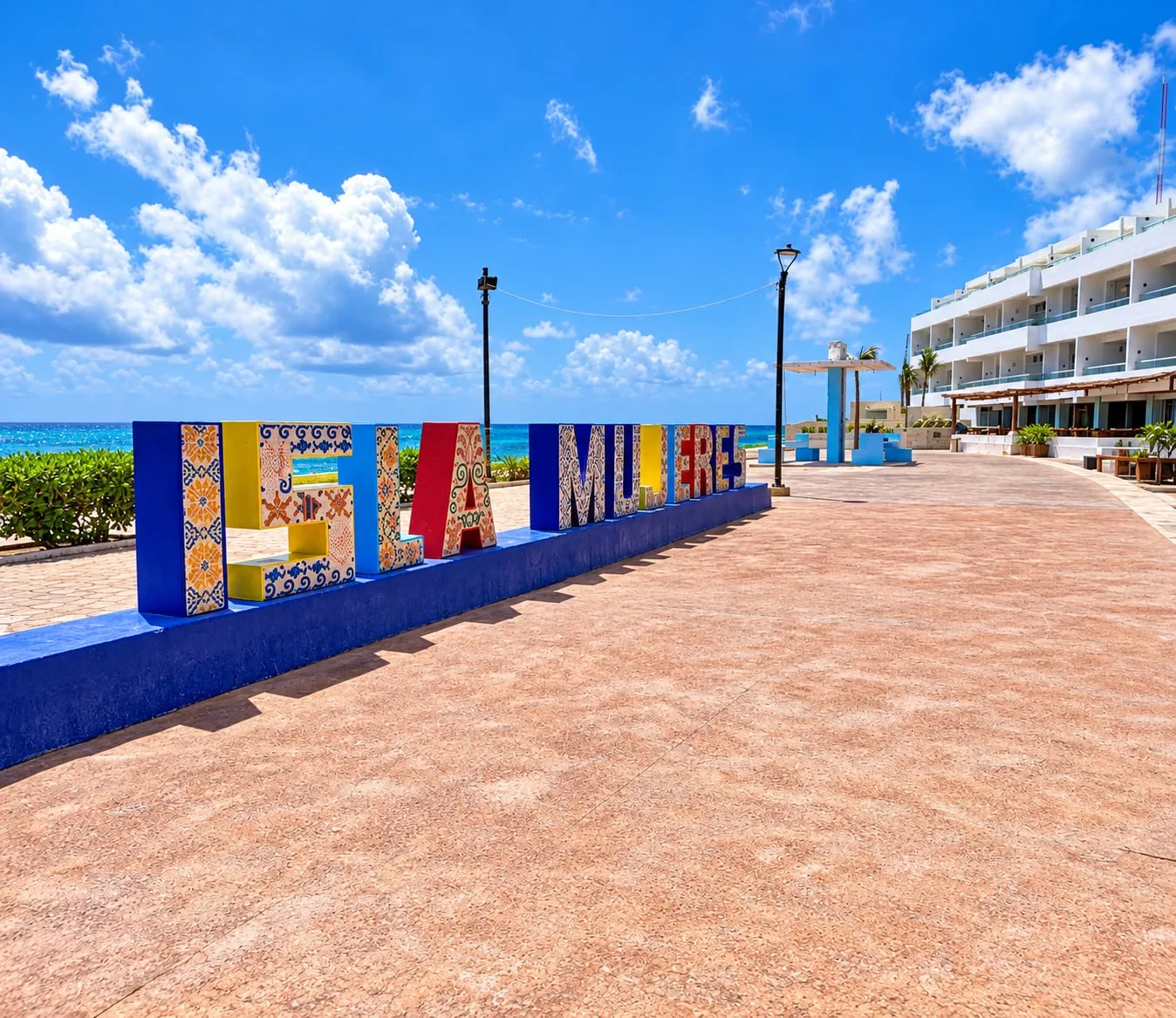 Letras de colores con el nombre de Isla Mujeres frente al mar, en un andador junto a la playa