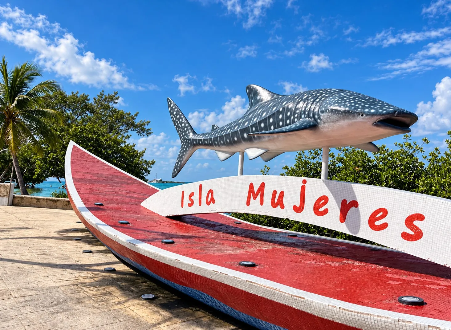 Monumento al tiburón ballena junto al mar en Isla Mujeres, sobre una lancha roja con el letrero "Isla Mujeres"